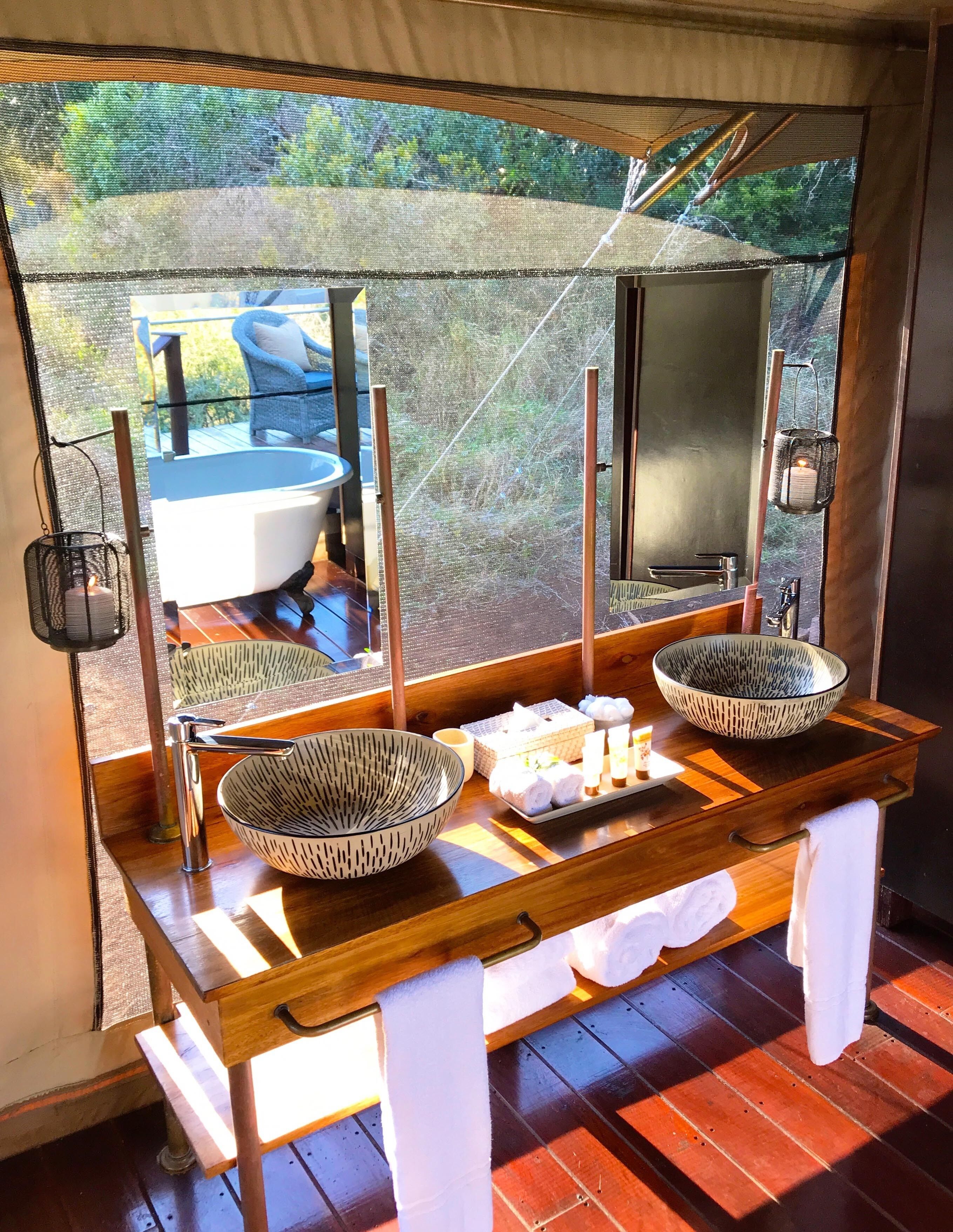 A bathroom with two large bowls, a mirror, and a wooden vanity.