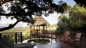 A wooden deck with a thatched-roof gazebo, a pool, and lounge chairs. - Thanda Safari (Hluhluwe)