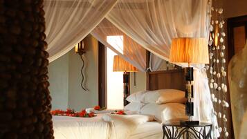 A bedroom with a bed, bedside lamps, a wooden ceiling, and a decorative canopy.