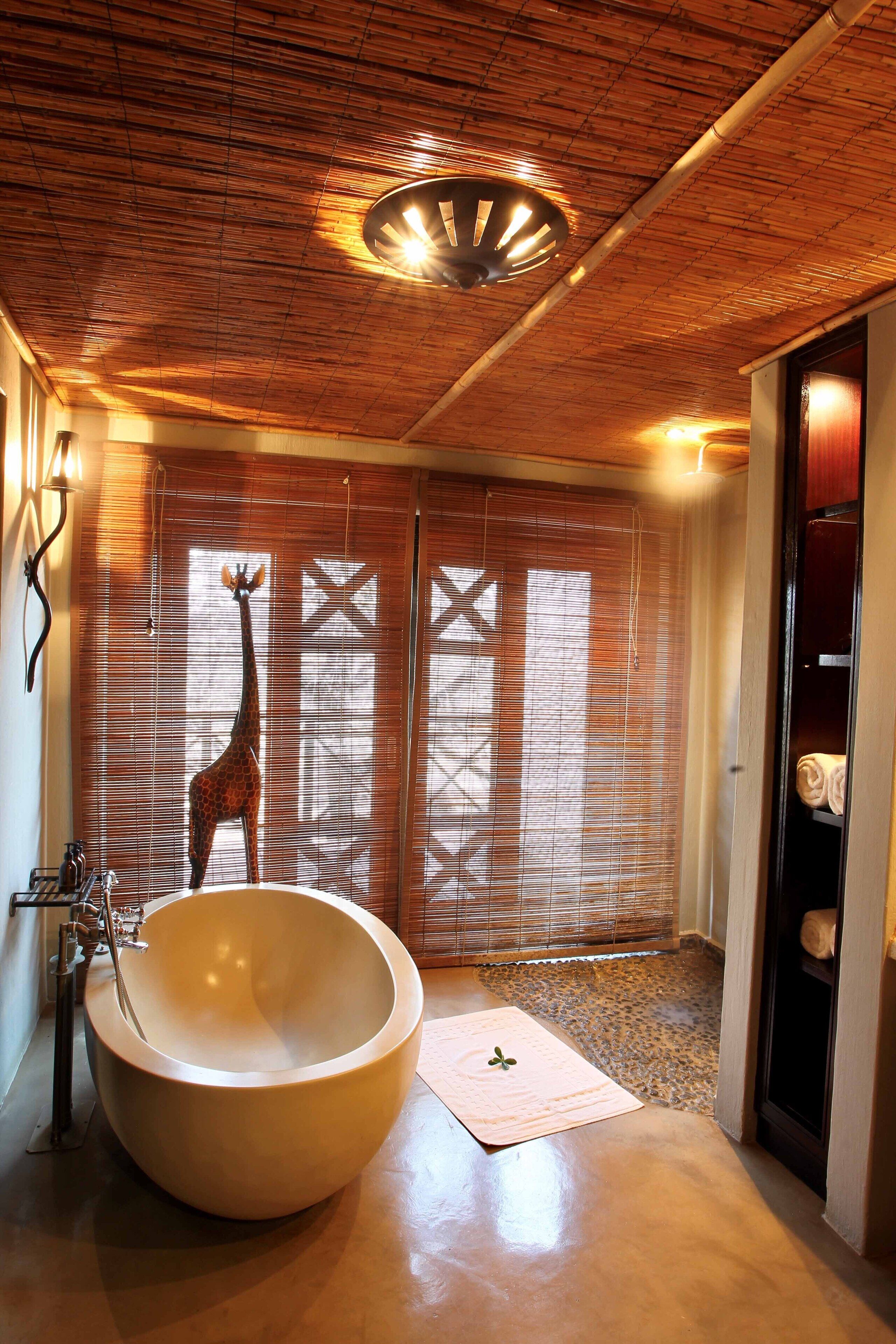 A bathroom with a large bathtub, a giraffe sculpture, and bamboo ceiling.