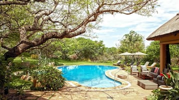 Una piscina al aire libre, sillones reclinables de piscina