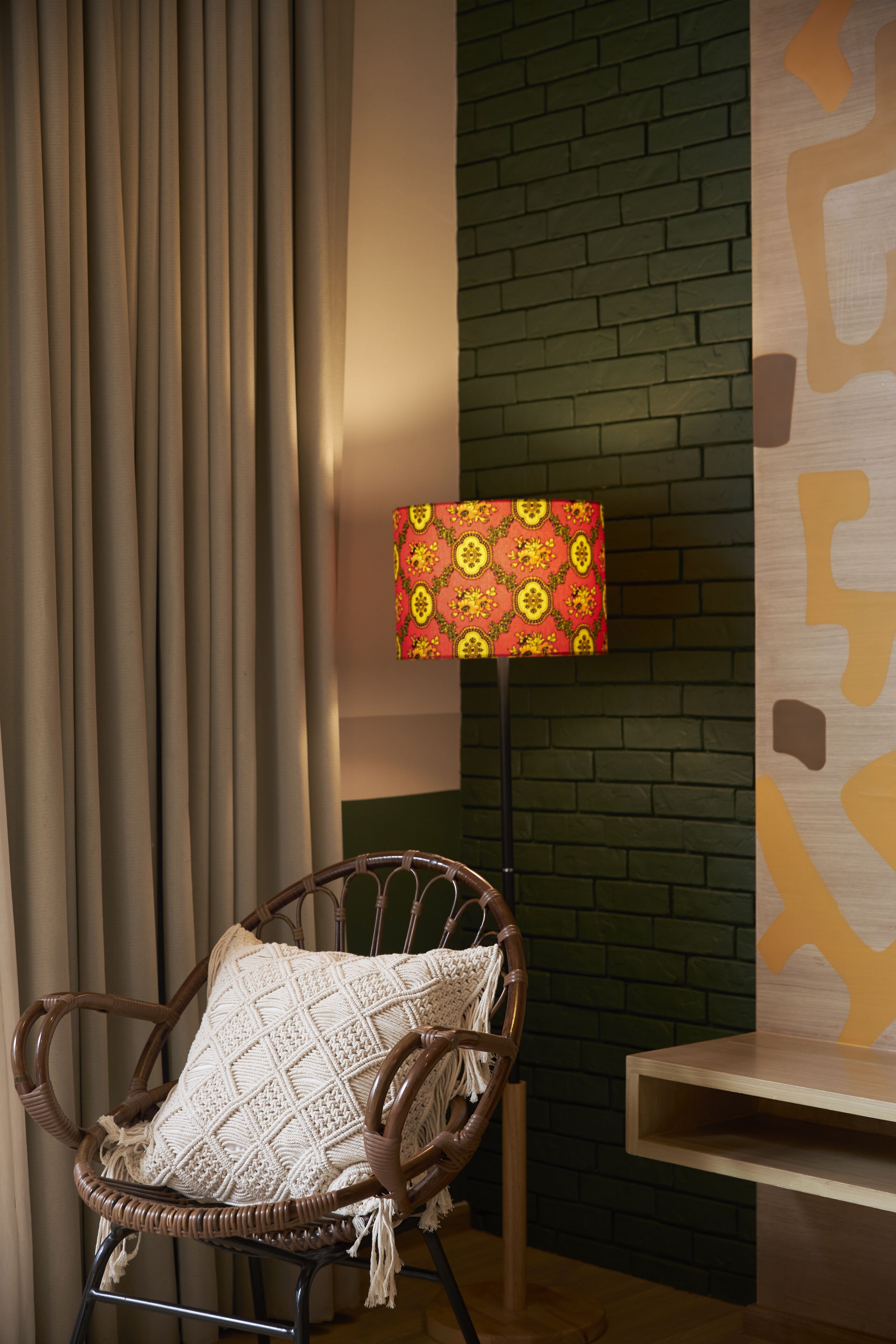 Une chaise en osier avec un coussin texturé, un lampadaire avec un abat-jour à motifs et un mur en briques.