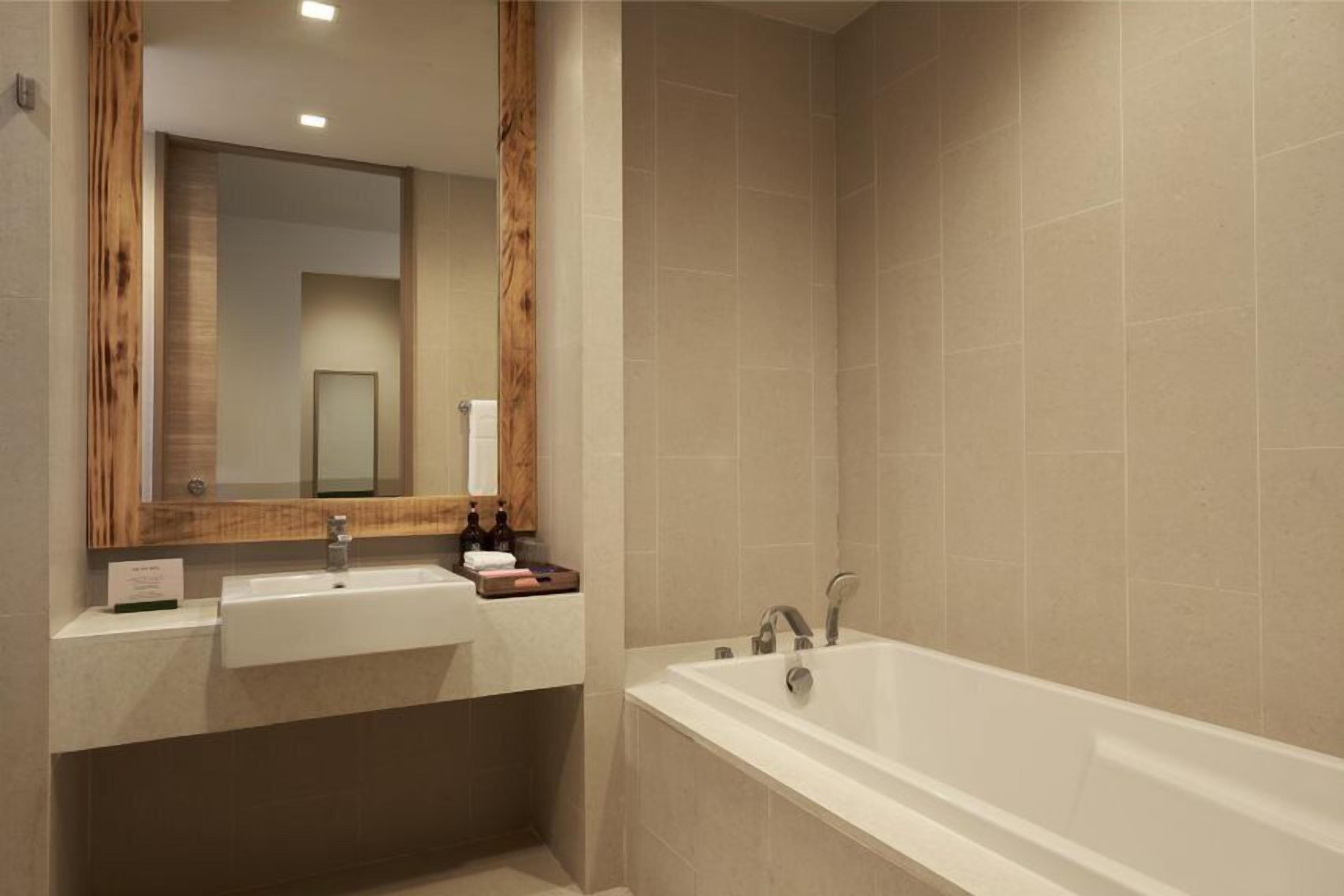 A modern bathroom with a large mirror, two sinks, and a bathtub.
