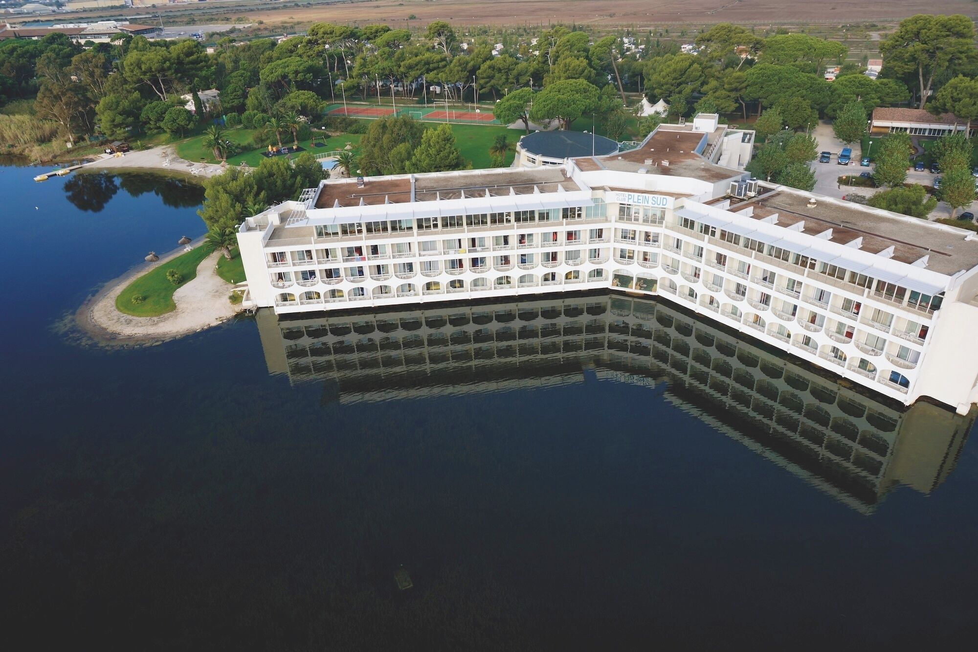 A large, multi-story hotel with balconies, situated by a body of water.