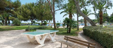 Un parque con mesa de ping pong y banco.