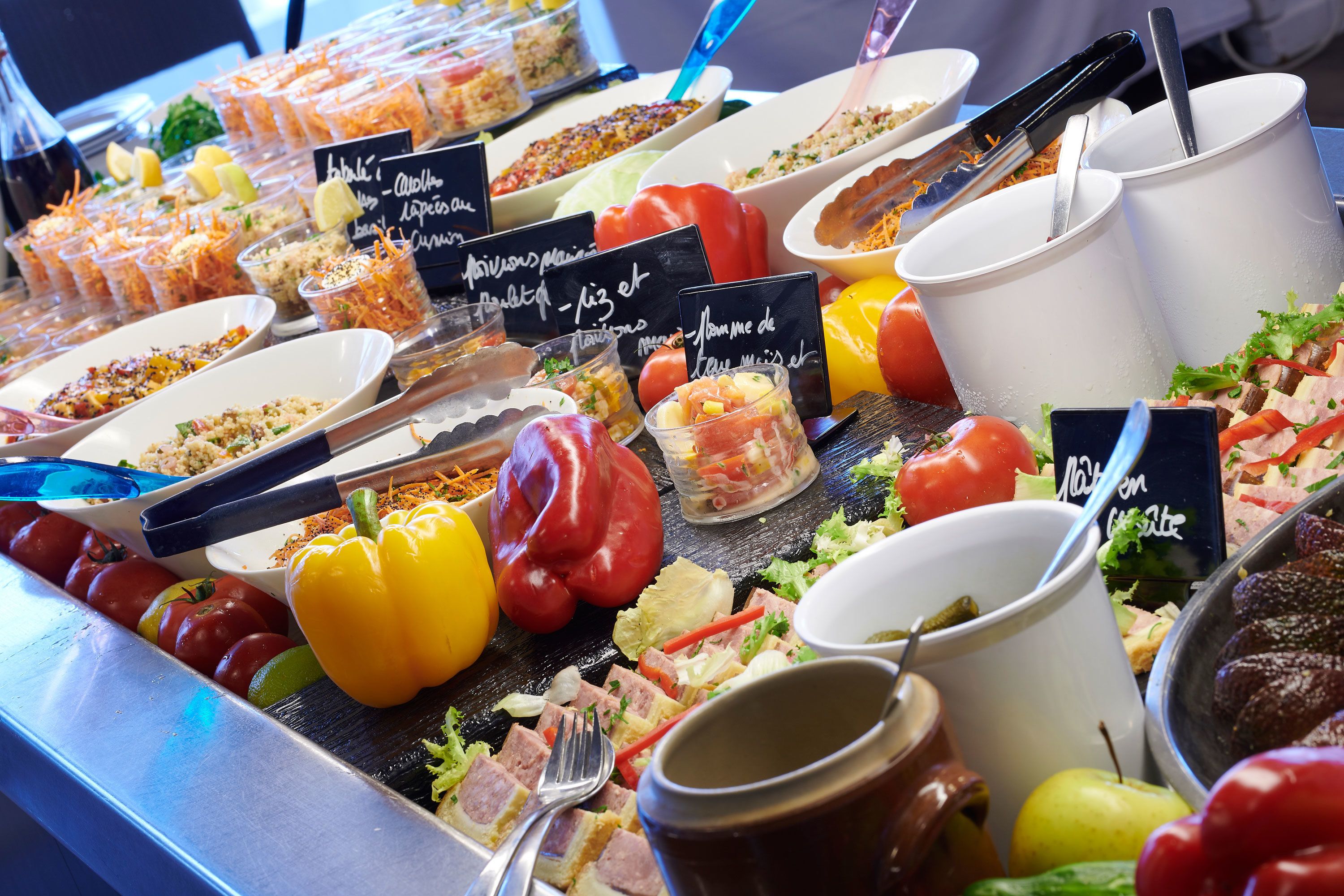 Ein Buffet mit verschiedenen Speisen und Getränken, darunter Salate, Fleisch und Gemüse.
