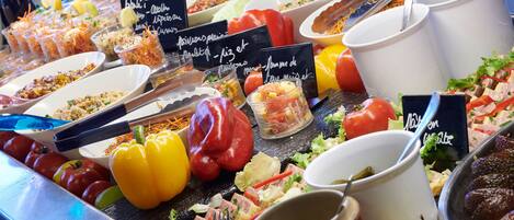 Ein Buffet mit verschiedenen Speisen und Getränken, darunter Salate, Fleisch und Gemüse.