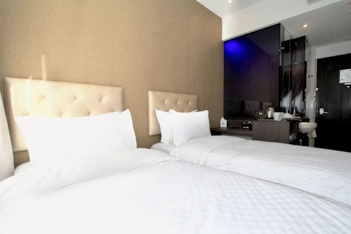 A hotel room with two beds, a bathroom, and a large mirror.