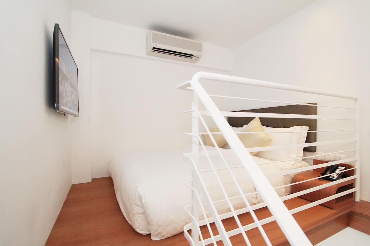 Ein Schlafzimmer mit Bett, weißem Geländer und einem kleinen Nachttisch mit Telefon.