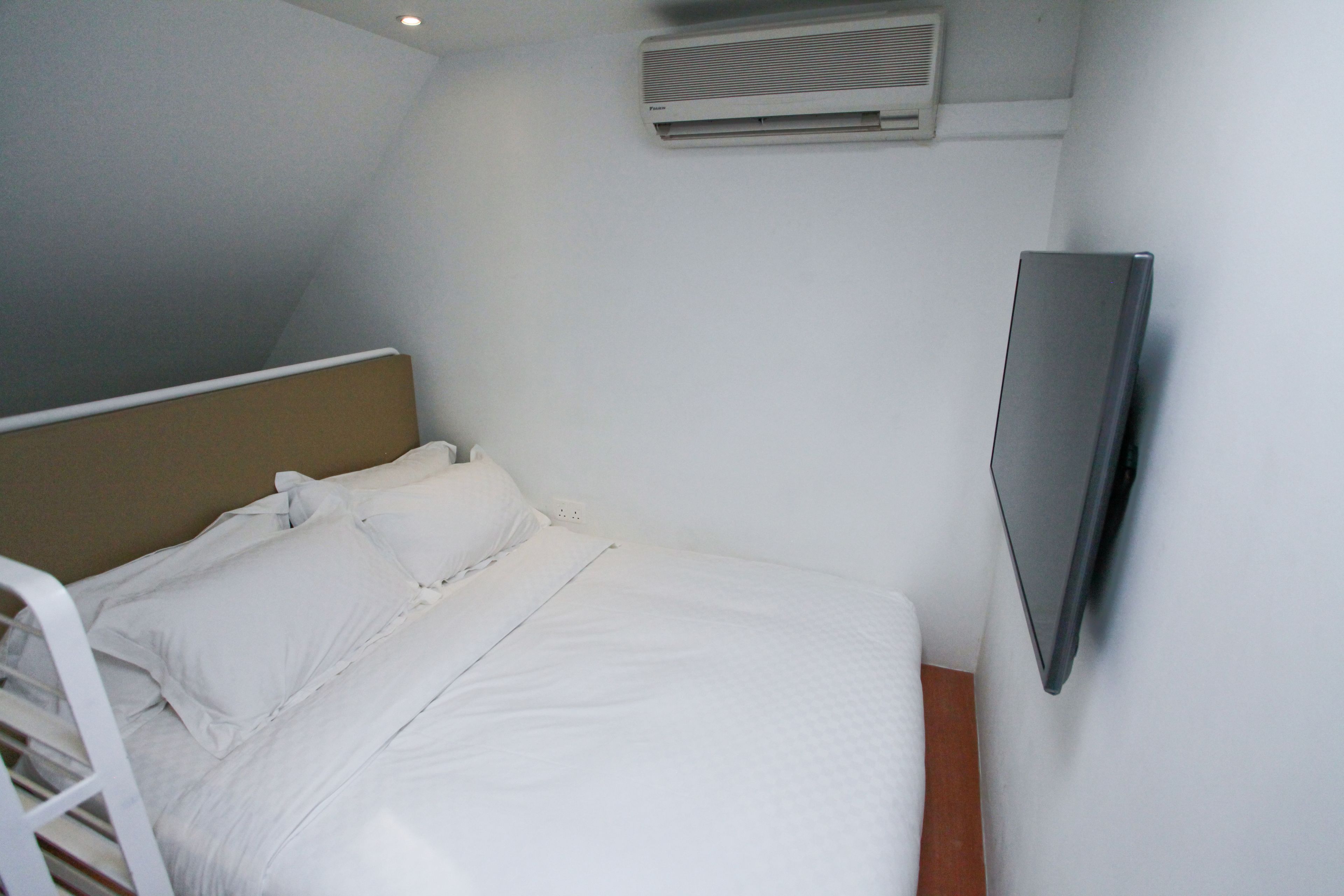A small, neatly made bed with white linens in a compact room.
