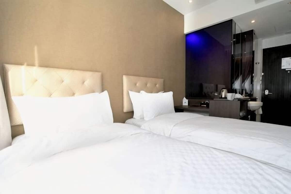 Ein Hotelzimmer mit zwei Betten, einem Badezimmer und einem großen Spiegel.