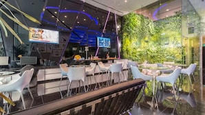 Zona de bar moderna con separador de vidrio, asientos y pared vertical con jardín.