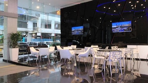 Un restaurante moderno con fachada de vidrio, sillas blancas y piso de baldosas negras.