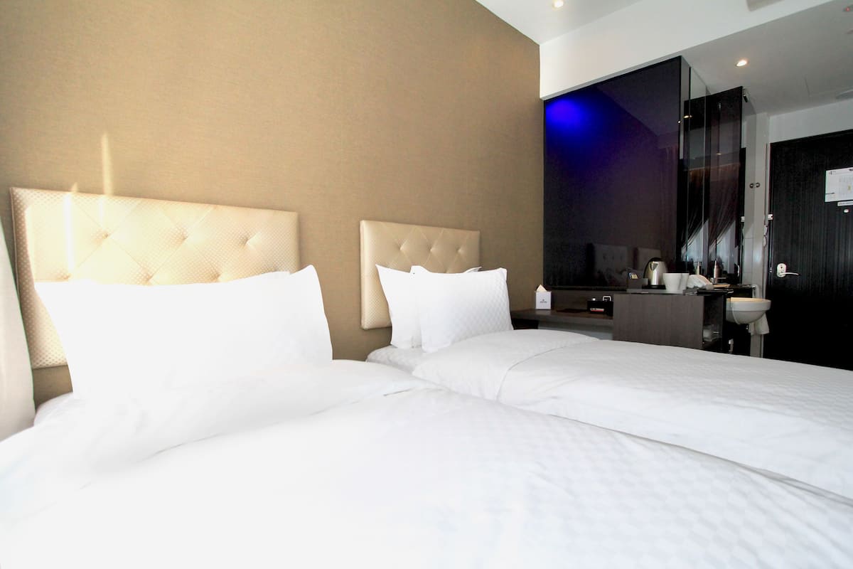 Ein Hotelzimmer mit zwei Betten, einem großen Spiegel und einem modernen Badezimmer.