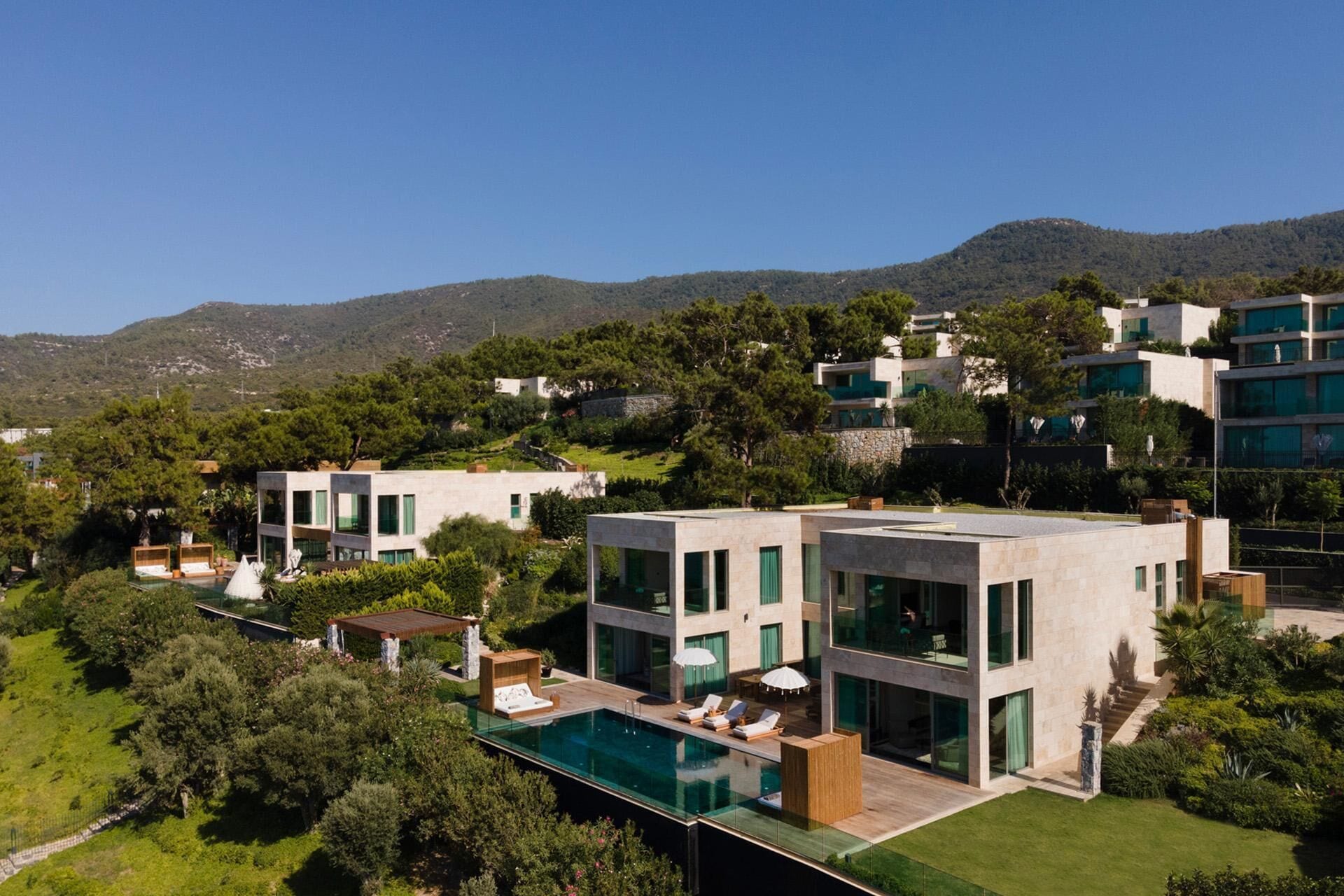 A modern villa with a swimming pool, multiple bedrooms, and a view of the surrounding hills.