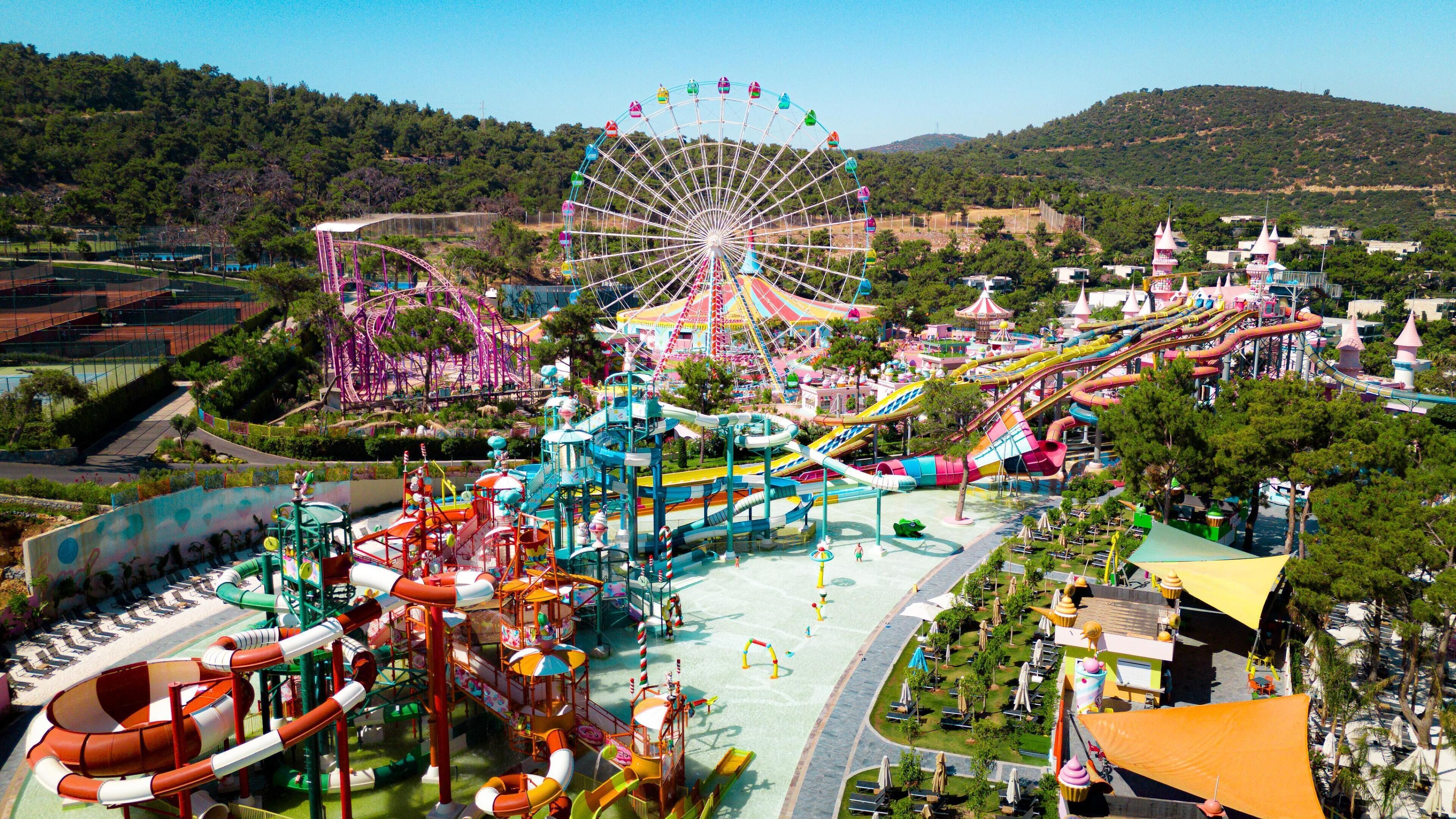 Un parc d’attractions doté d’une grande roue, de manèges aquatiques colorés et de diverses structures de divertissement.