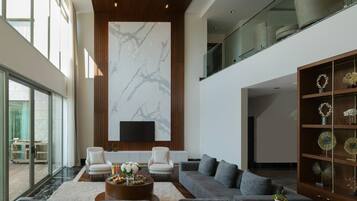 A spacious living area with a large marble wall, modern furniture, and a glass railing overlooking a deck.