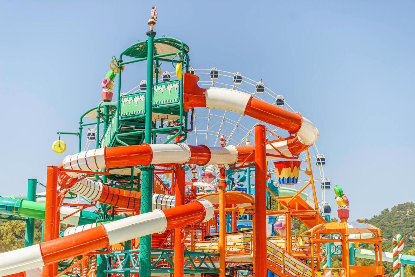 Een kleurrijk attractiepark met een reuzenrad en diverse waterglijbanen.