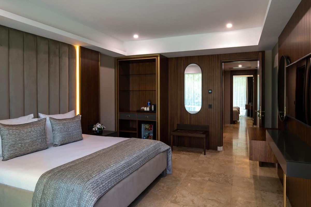 Una habitación de hotel moderna con una cama grande, un armario, un tocador y un televisor.