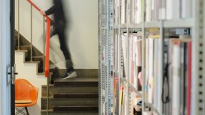 Un escalier avec des rampes en métal, et une personne qui monte.