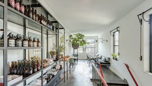 Un intérieur moderne avec un long couloir, des étagères remplies de bouteilles, un coin repas et un escalier.