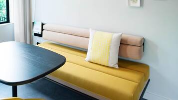 A modern living room with a yellow sofa, a black table, and a yellow chair.