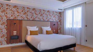 Une chambre moderne avec un grand lit, une tête de lit en bois et un papier peint à motifs floraux.
