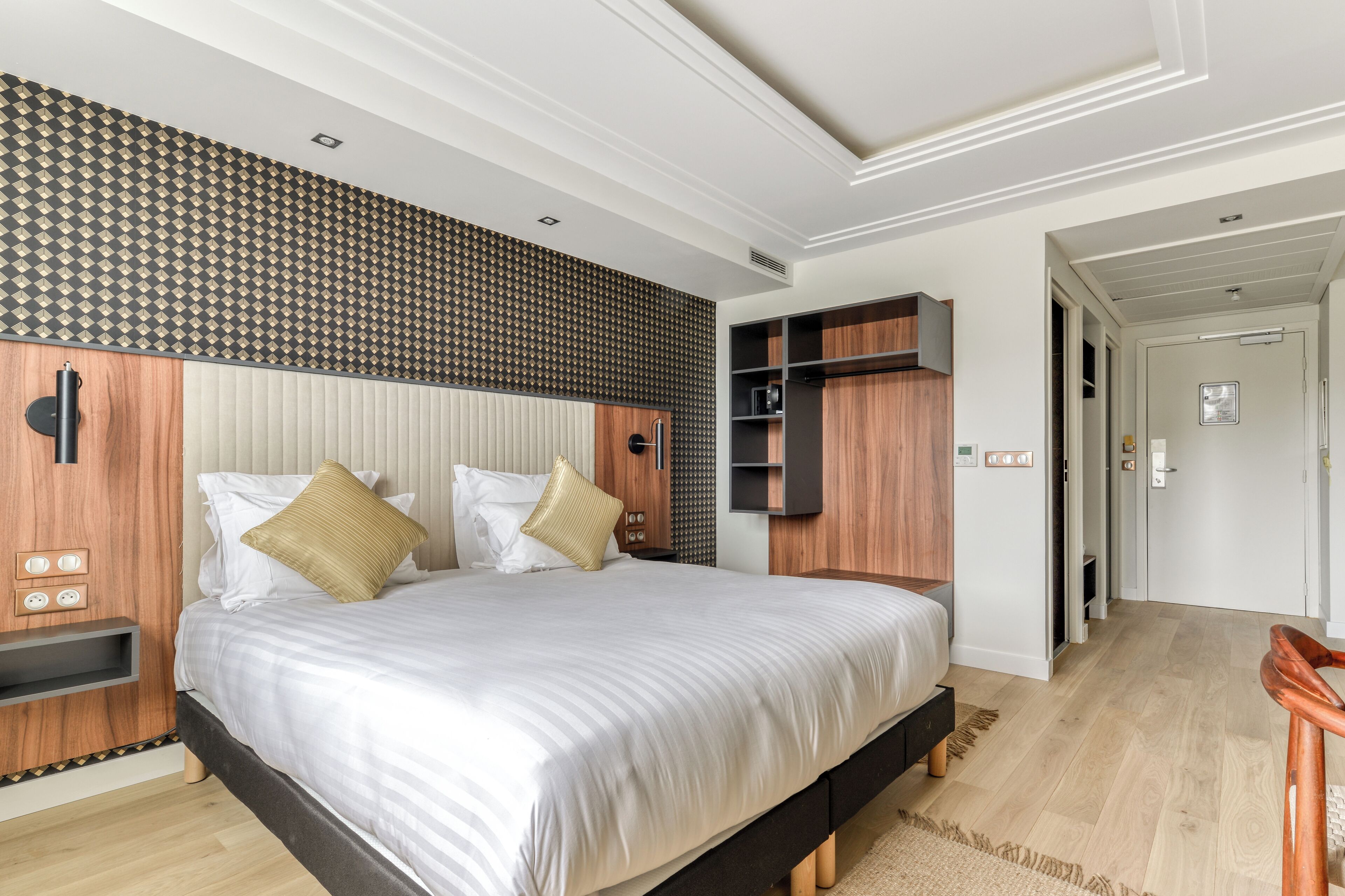 Un dormitorio moderno con una cama grande, estanterías empotradas de madera y un papel tapiz estampado.