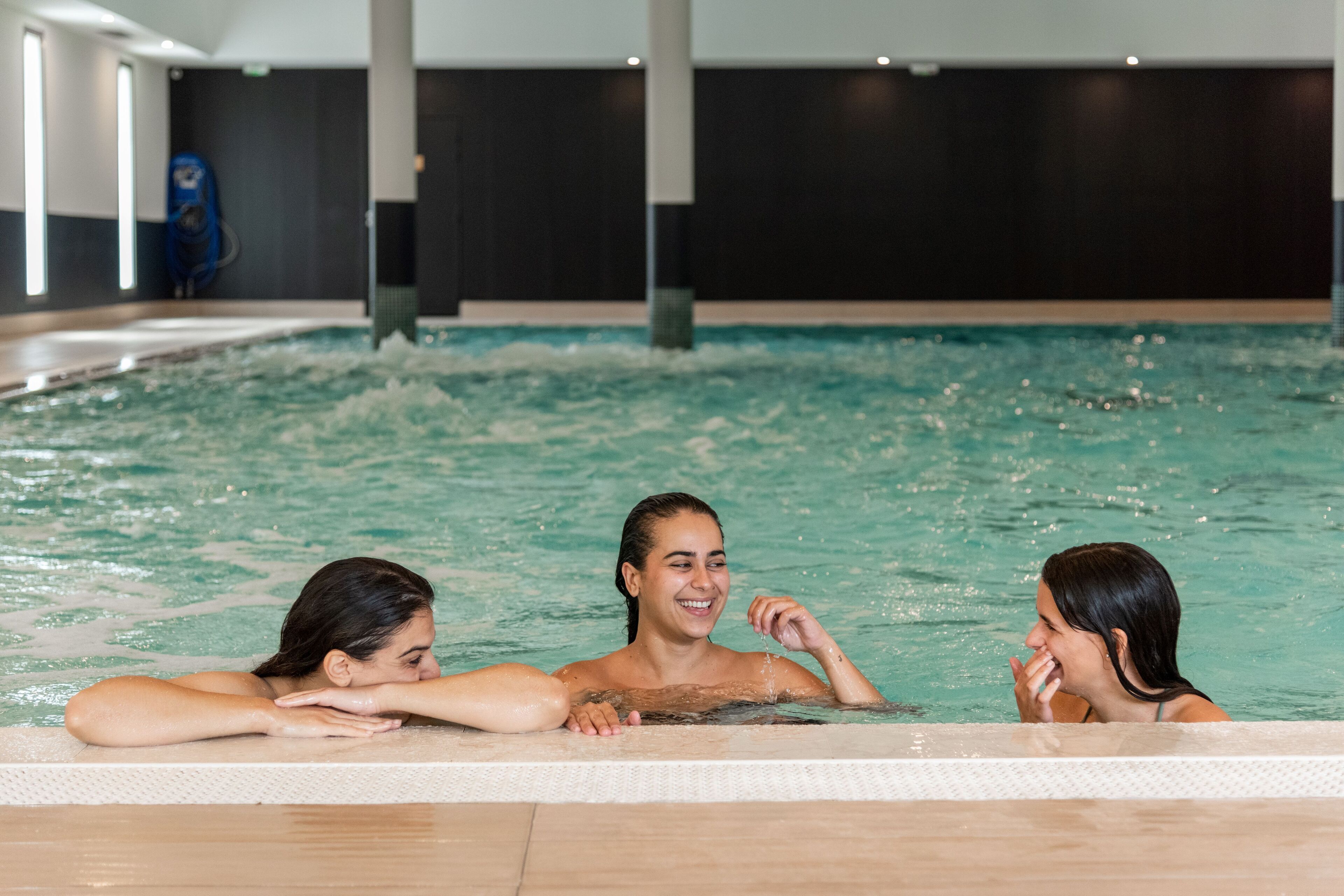 An indoor swimming pool with three people in the water.
