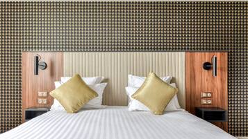 Una habitación de hotel con una cama grande, dos mesitas de noche, un cabecero de madera y un papel pintado decorativo.
