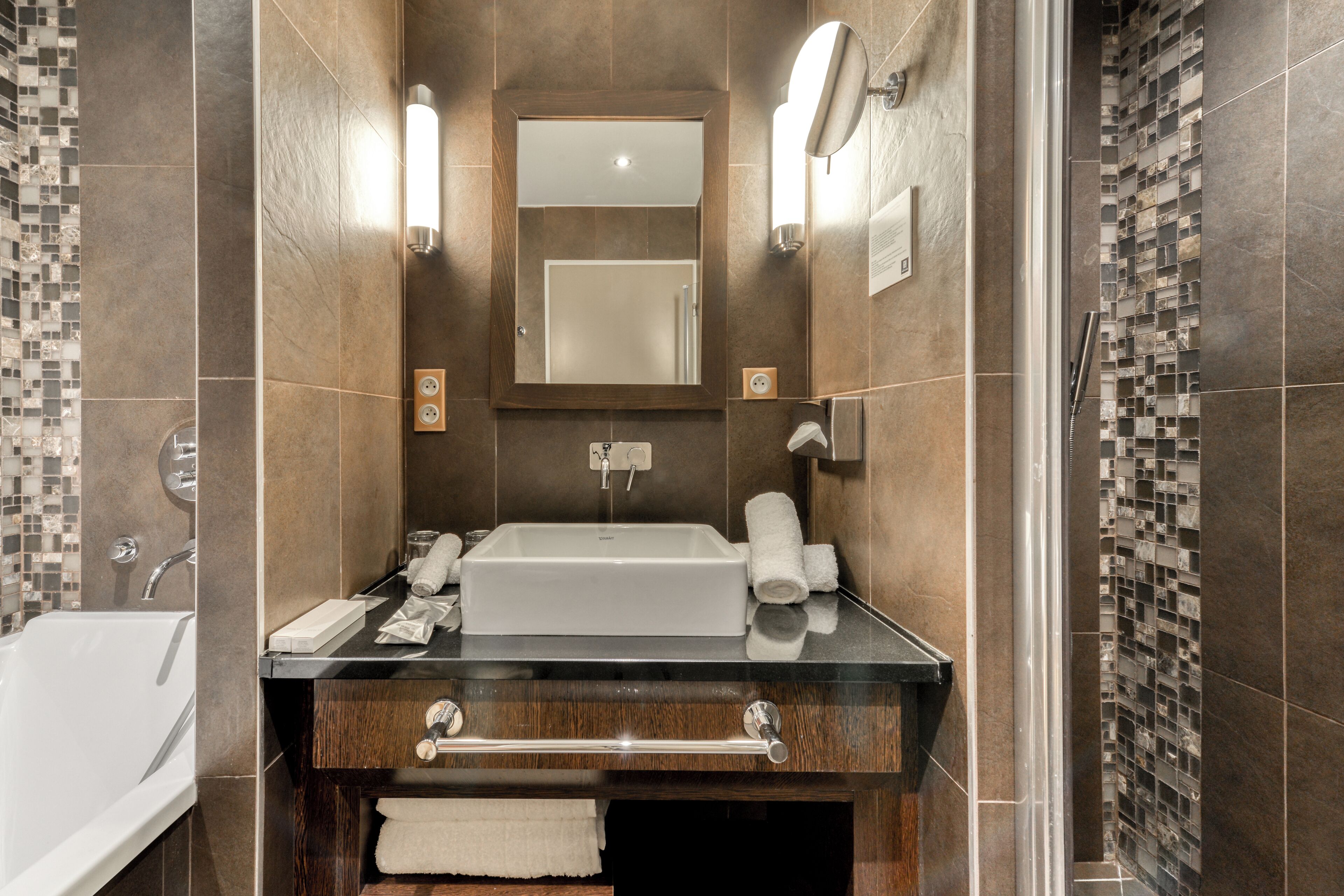 A modern bathroom with a large sink, mirror, and towel rack.