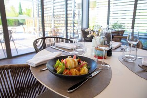 A dining table with a plate of food, wine glasses, and cutlery.