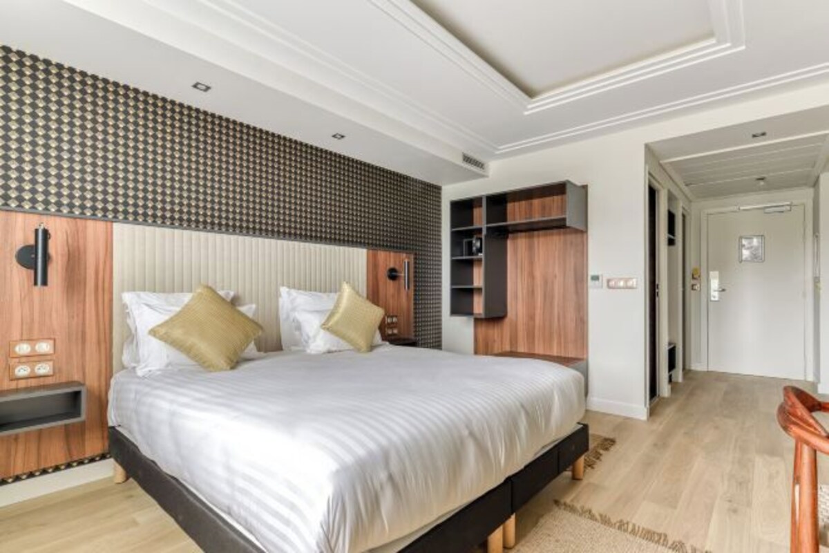 A modern bedroom with a large bed, built-in shelving, and a patterned wall.