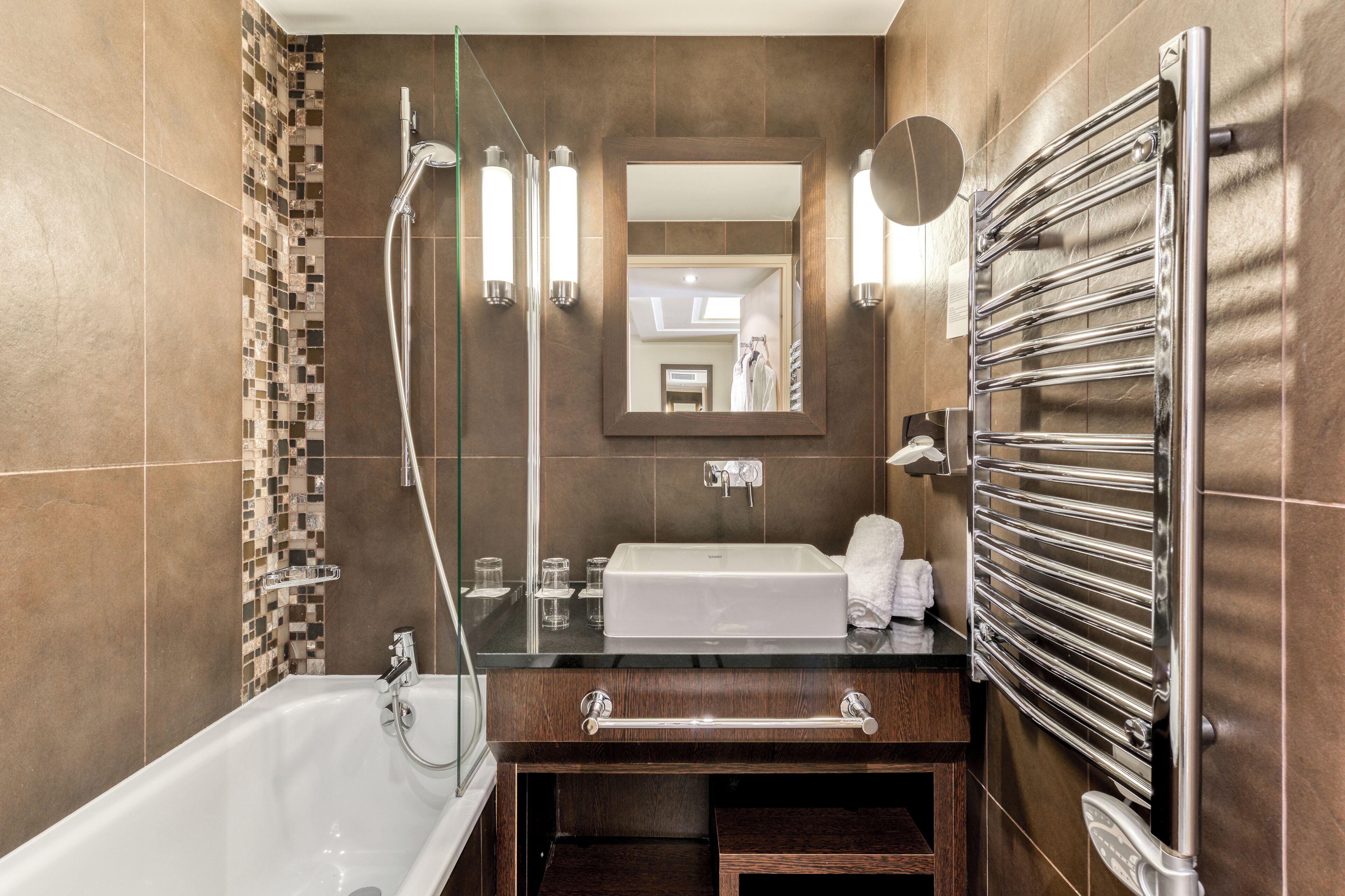 A modern bathroom with a bathtub, a vanity with a mirror, and a towel rack.