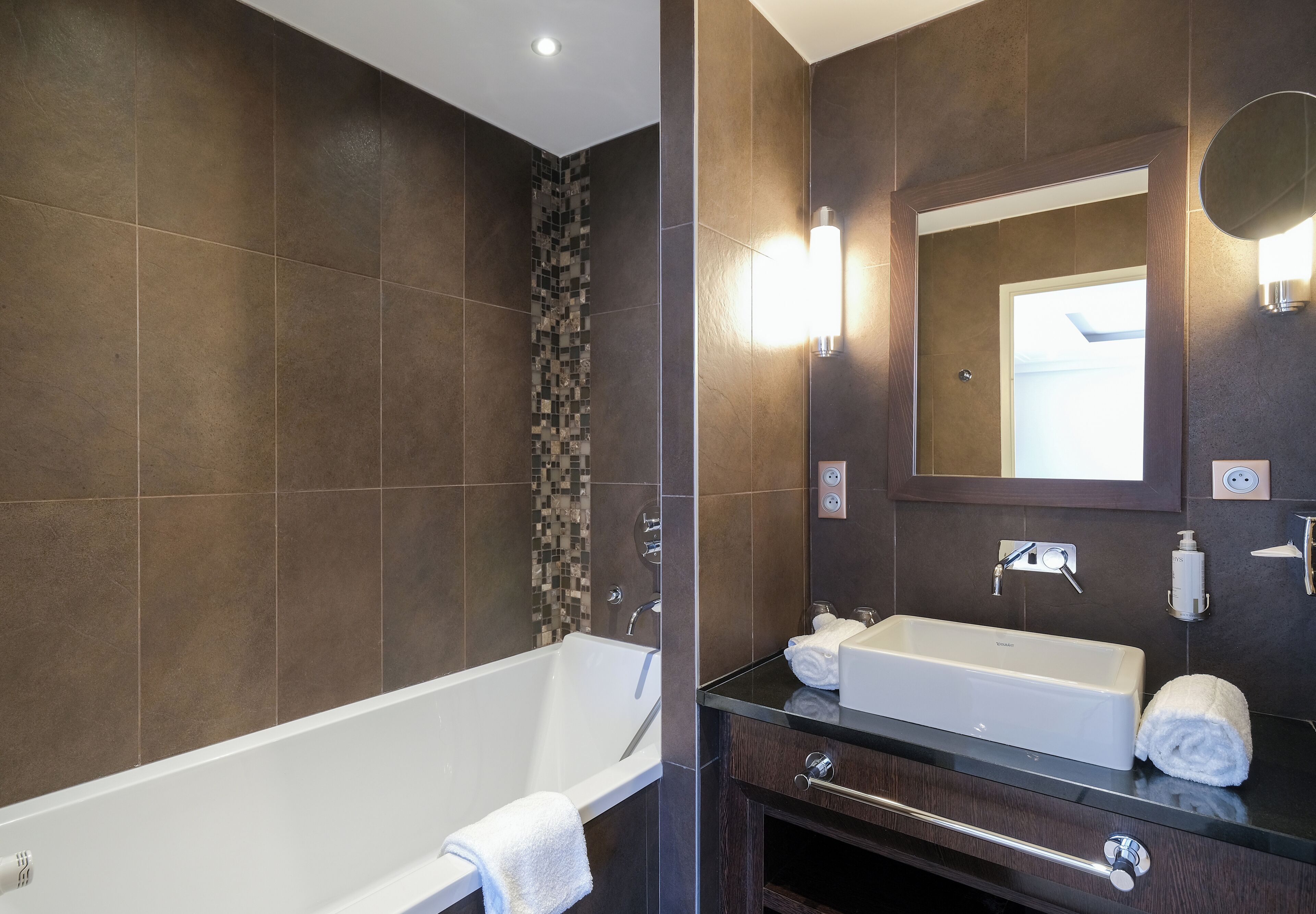 A modern bathroom with a bathtub, a sink, and a mirror.
