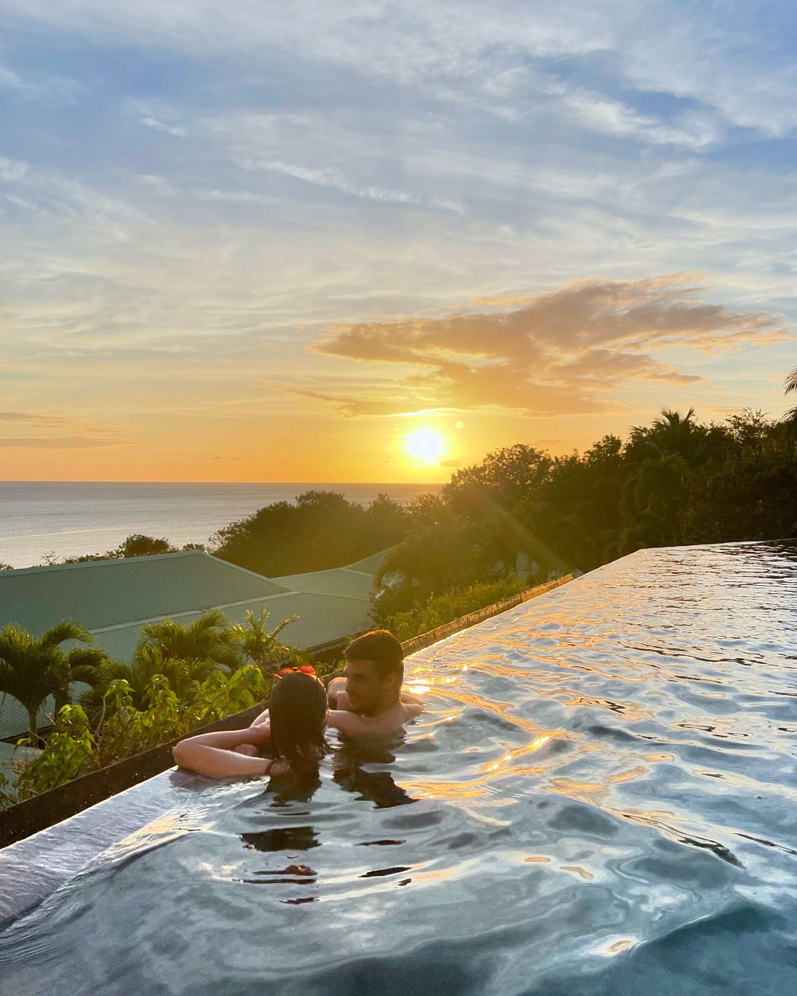 Una pareja relajándose en una piscina con vistas al atardecer.