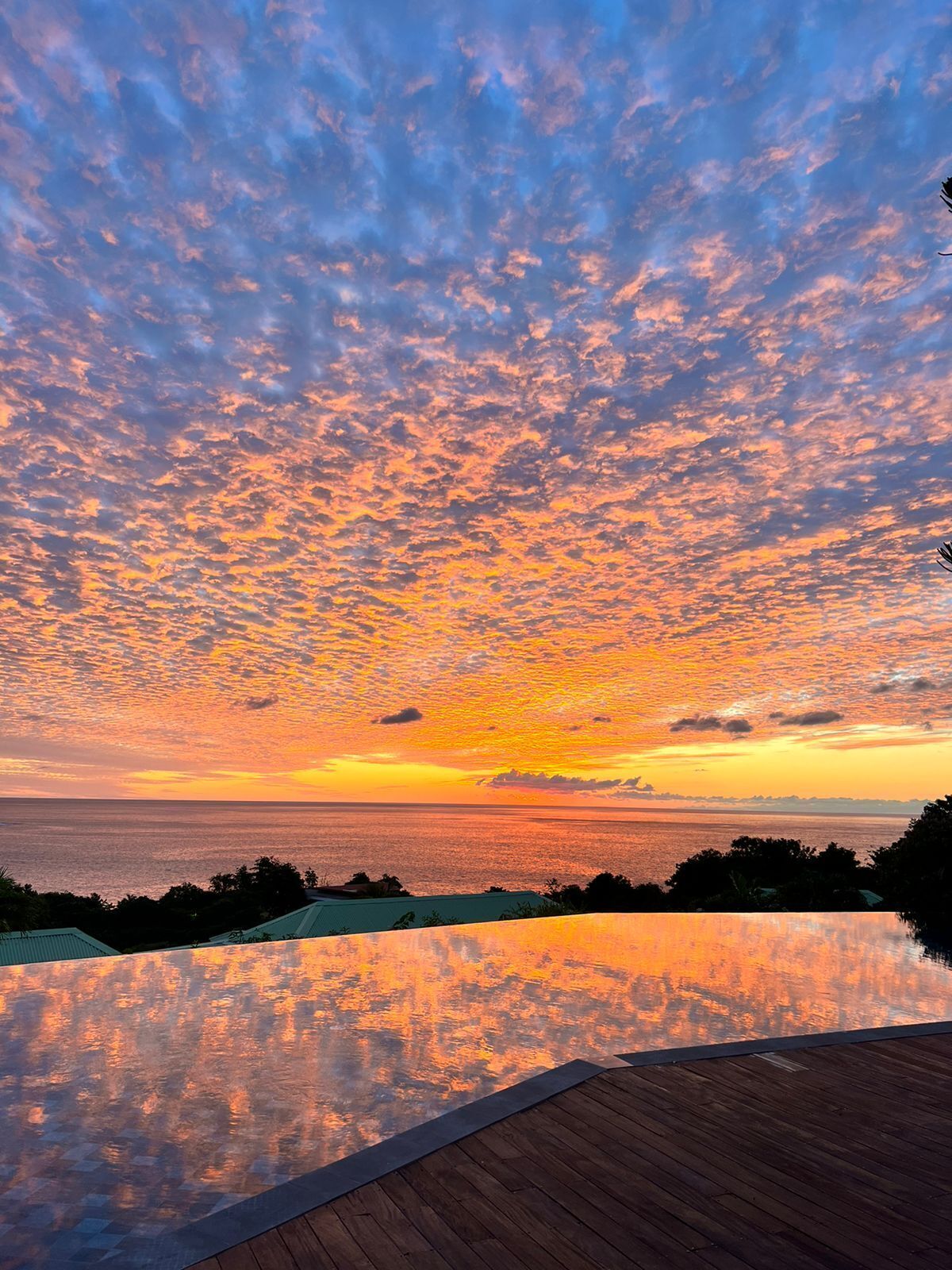Un atardecer sobre un cuerpo de agua con una cubierta de madera al frente.