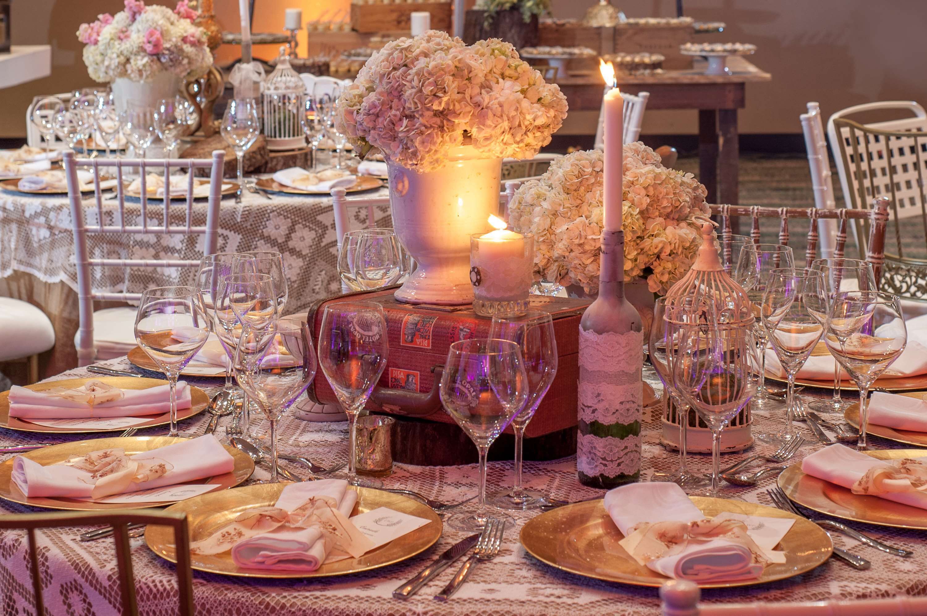 A table set for a formal dinner with multiple wine glasses, plates, and a lit candle centerpiece.