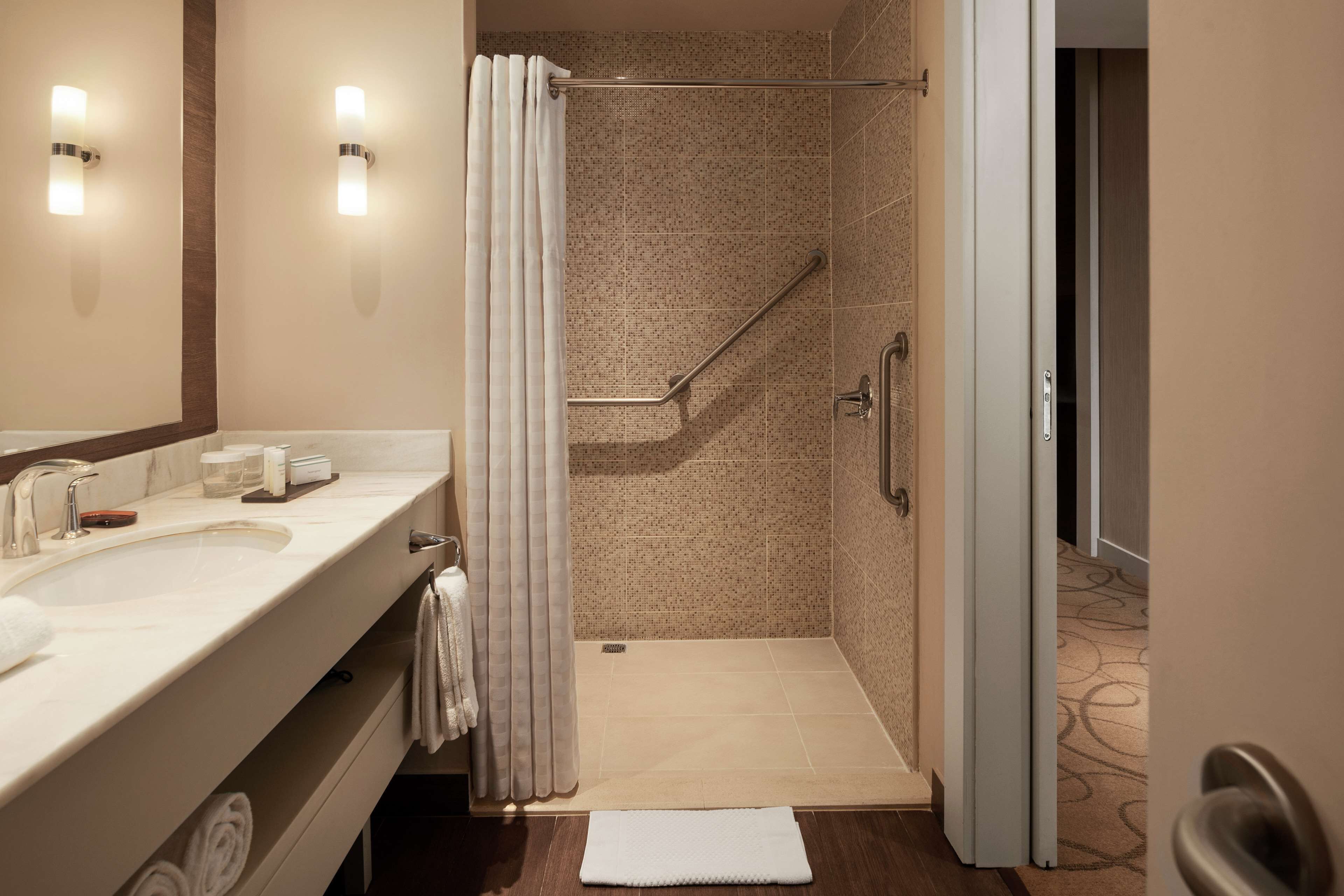A modern bathroom with a large sink, mirror, and shower area.