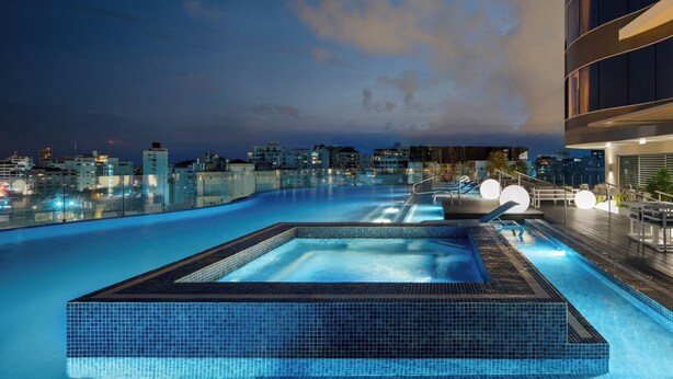 Une piscine sur le toit offrant une vue sur la ville au crépuscule.