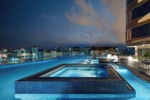 Une piscine sur le toit offrant une vue sur la ville au crépuscule.