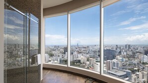 Une chambre située dans un immeuble de grande hauteur, offrant une vue panoramique sur la ville grâce à de grandes fenêtres.