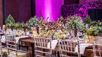 A dining table set with white tablecloths, wooden chairs, and floral centerpieces.
