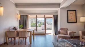 Ein modernes Hotelzimmer mit Essbereich, einer Couch und Blick auf die Stadt.
