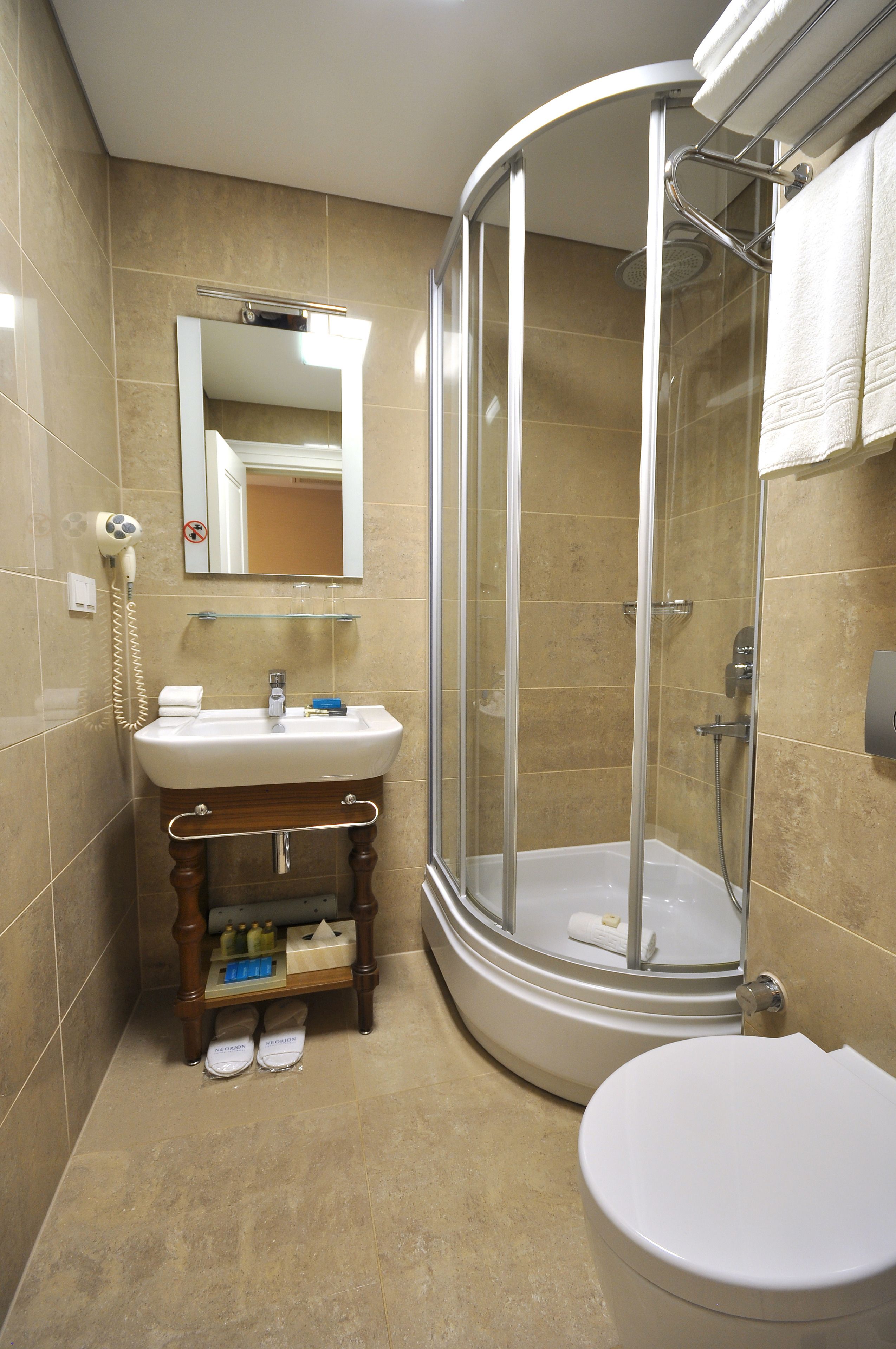 A bathroom with a glass-enclosed shower, a sink with a mirror above it, and a toilet.