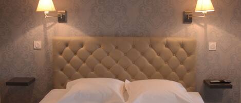 A neatly made bed with white linens and pillows, two bedside lamps, and a tufted headboard.