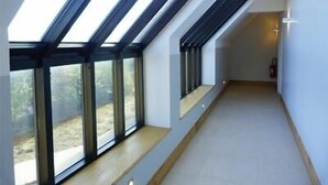 A corridor with skylights and large windows, leading to a room with a view of trees. - Auberge du Moulin à Vent, The Originals Relais (Manou)