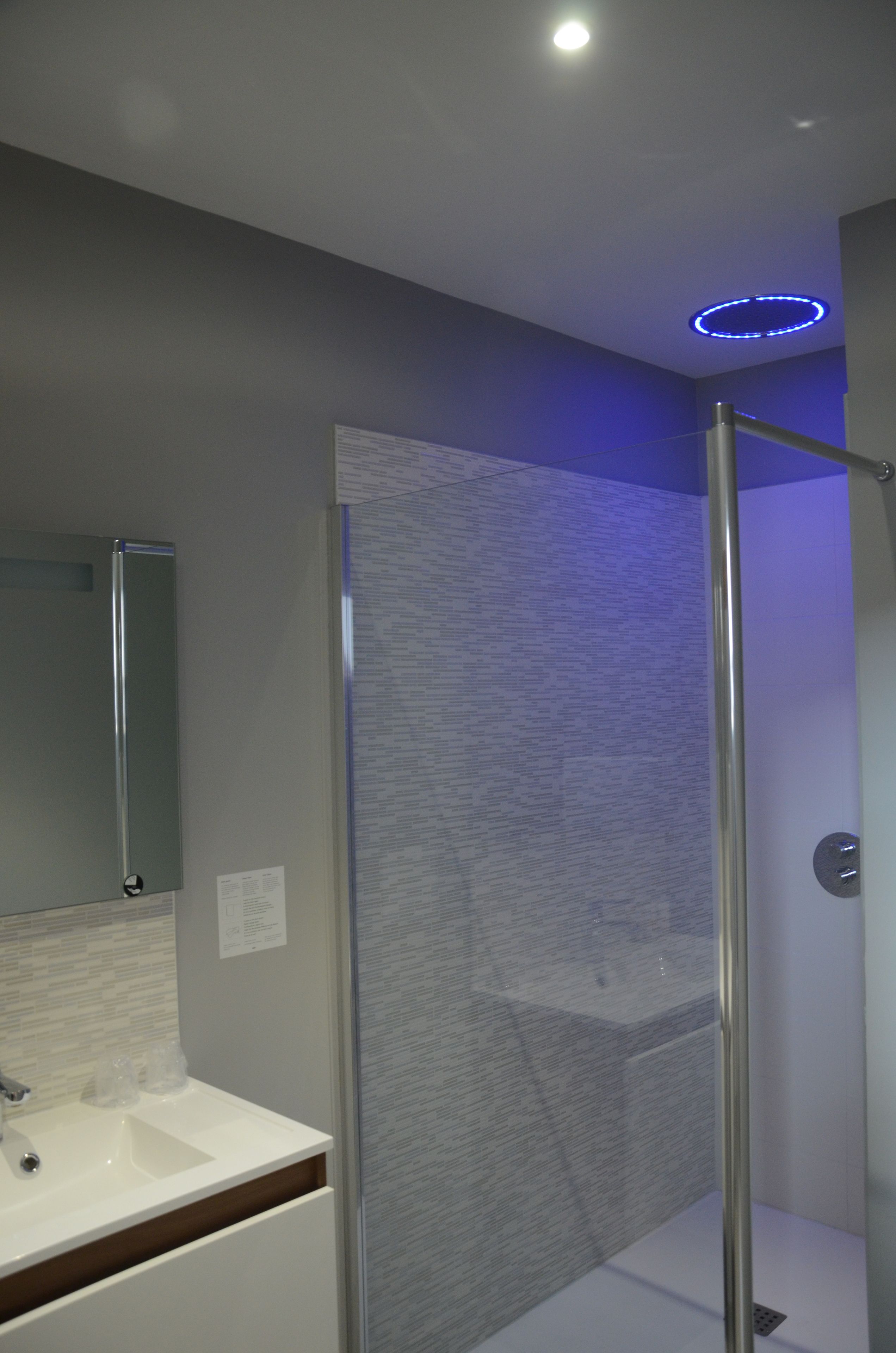 Une salle de bain moderne avec une douche à parois de verre, un lavabo blanc et un miroir.