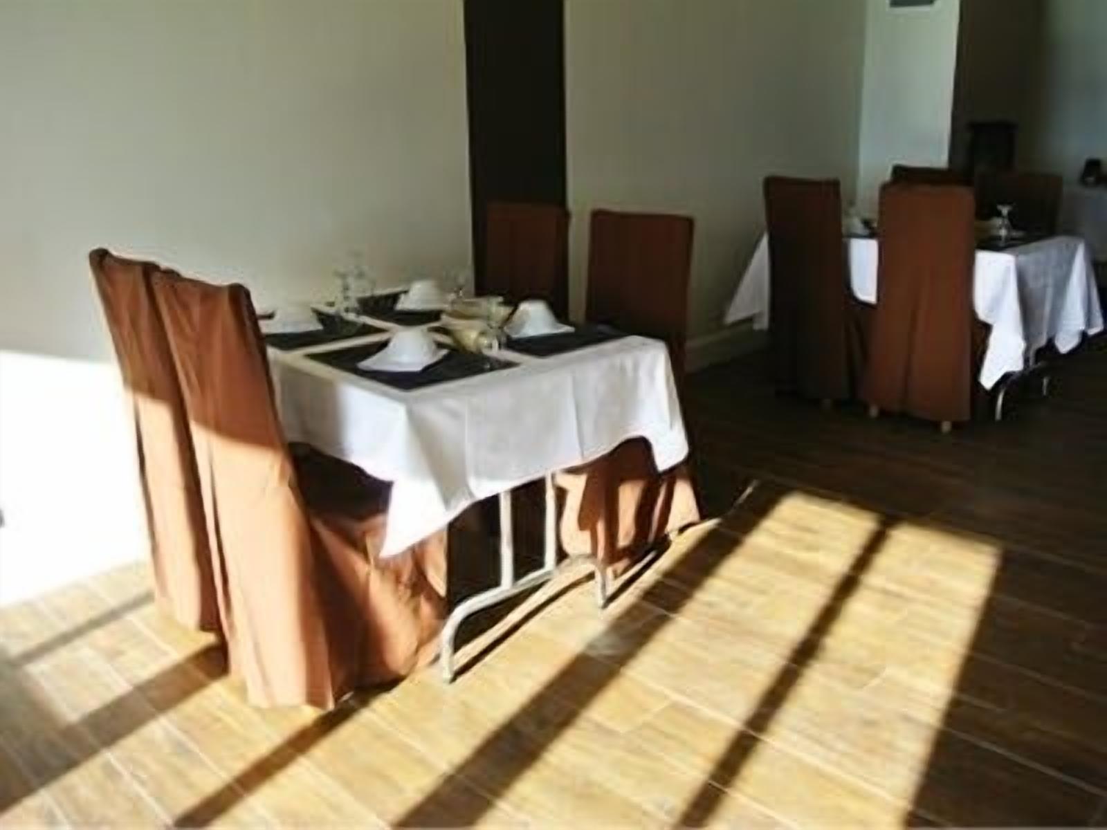 A dining area with a table set for four, wooden chairs, and a white tablecloth.