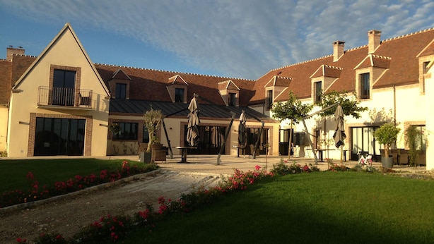 A courtyard with a building featuring a brick facade, a balcony, and a covered seating area. - Auberge du Moulin à Vent, The Originals Relais (Manou)